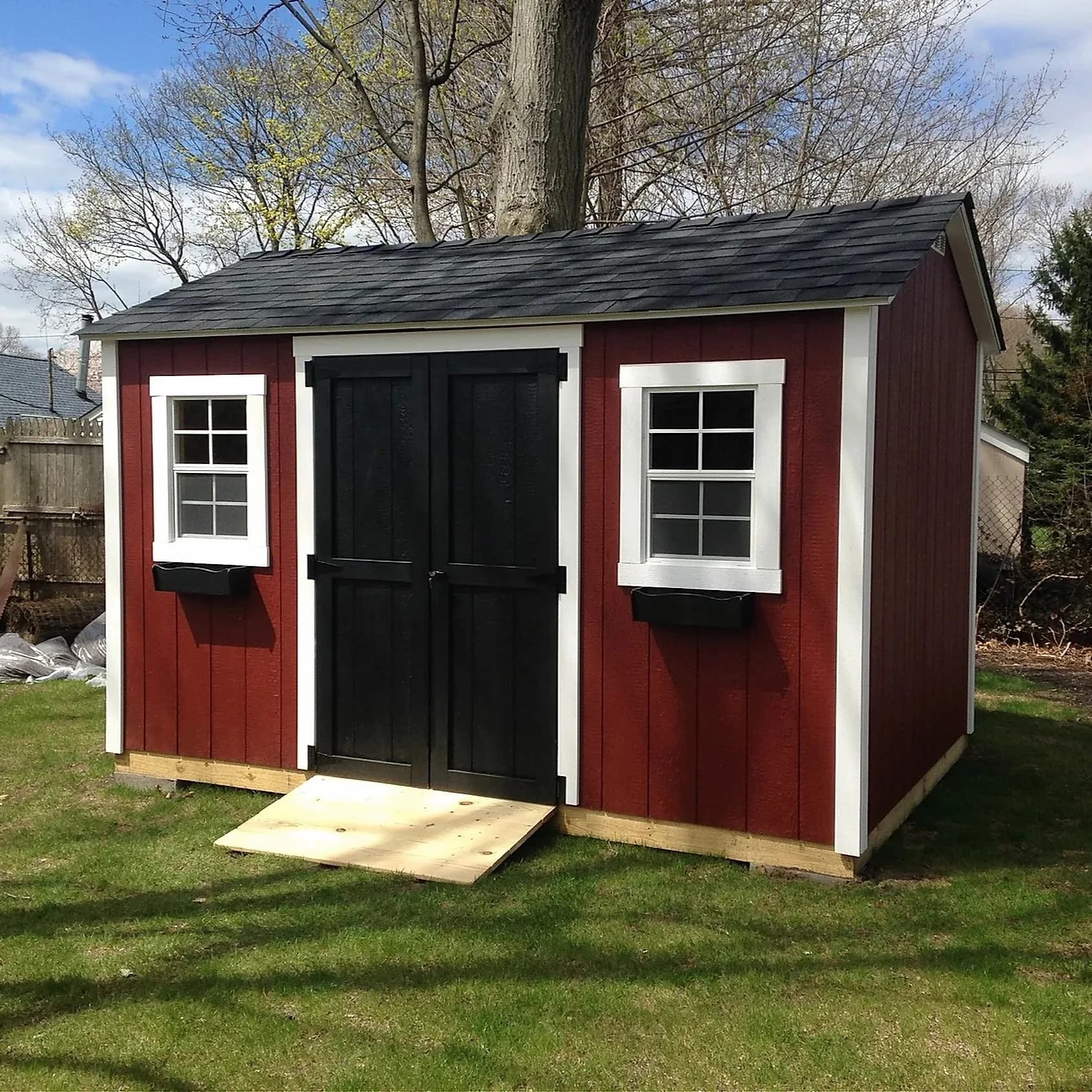 Red CNY Sheds backyard shed with black double doors and white window trim